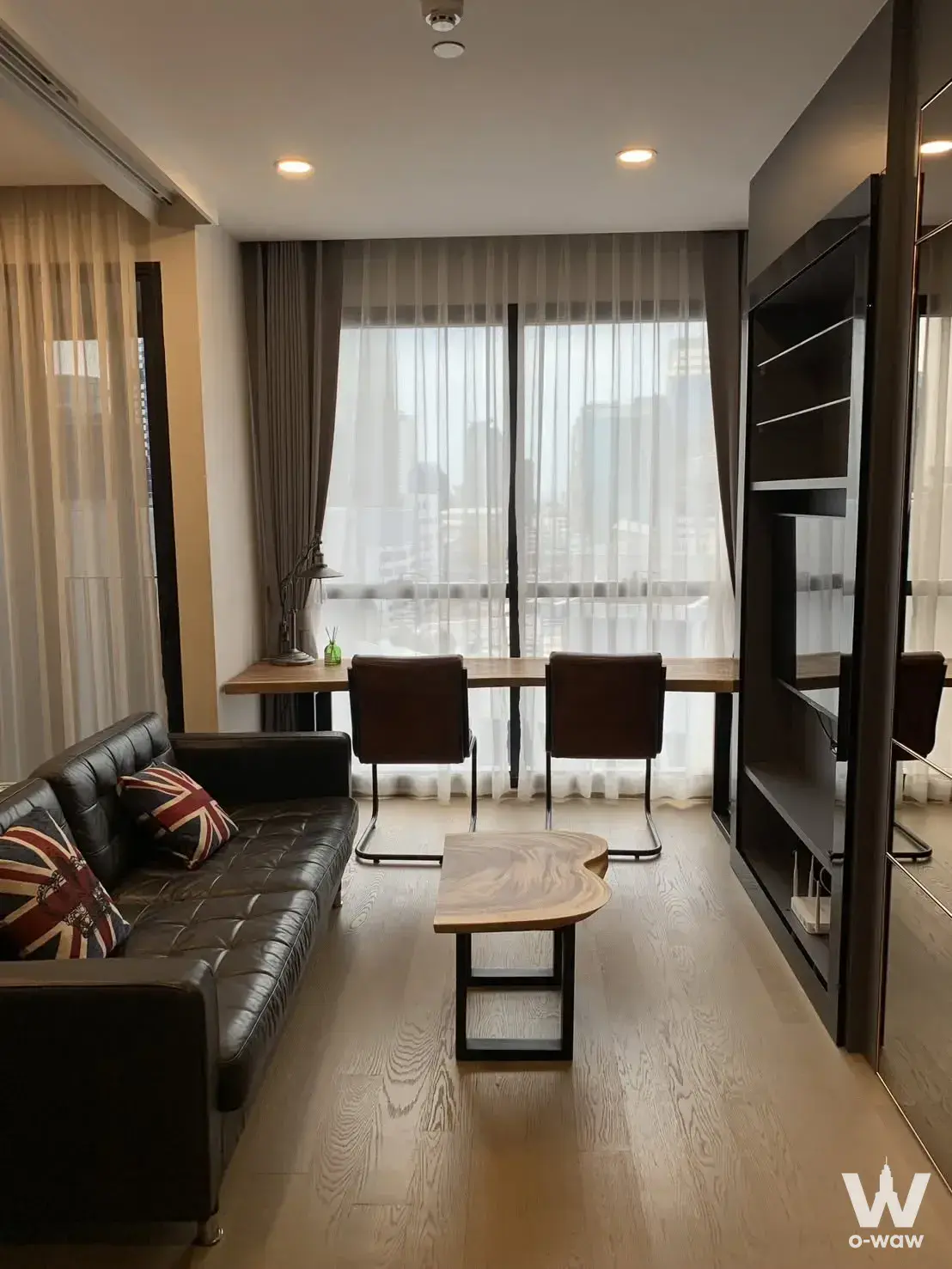 Modern condo living room with black Chesterfield sofa, Union Jack pillows, and floor-to-ceiling mirrored wardrobe