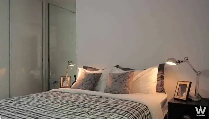 Modern bedroom in Hyde Sukhumvit 13 rental with queen bed, mirrored closets, and ambient lamp lighting