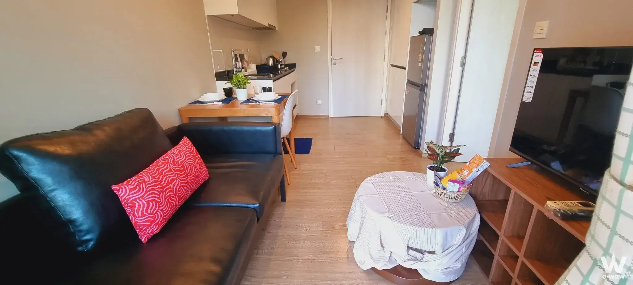 Modern 1-bed rental at Maestro 39 Sukhumvit with open-plan living area, dark sofa, and compact kitchenette
