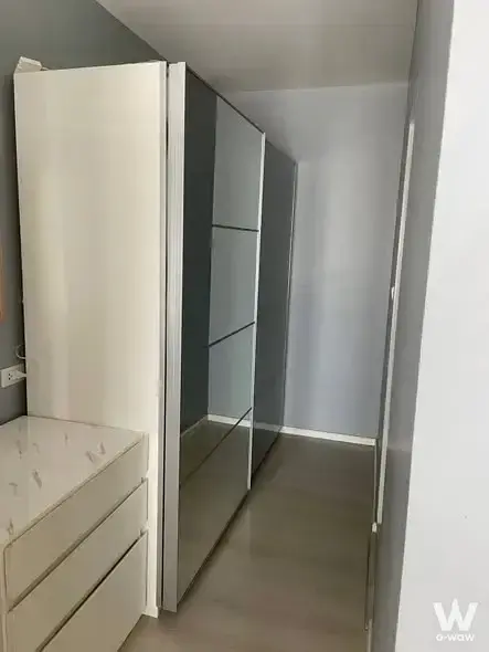 Modern walk-in closet with glossy white wardrobe, mirrored sliding doors, and marble-effect vanity in Aspire Sukhumvit 48