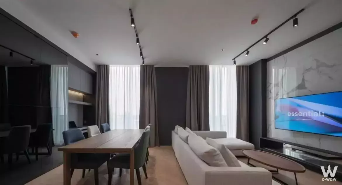 Modern living and dining area in 1-bed condo for rent at Noble BE19 with grey sofa, marble TV wall, and floor-to-ceiling