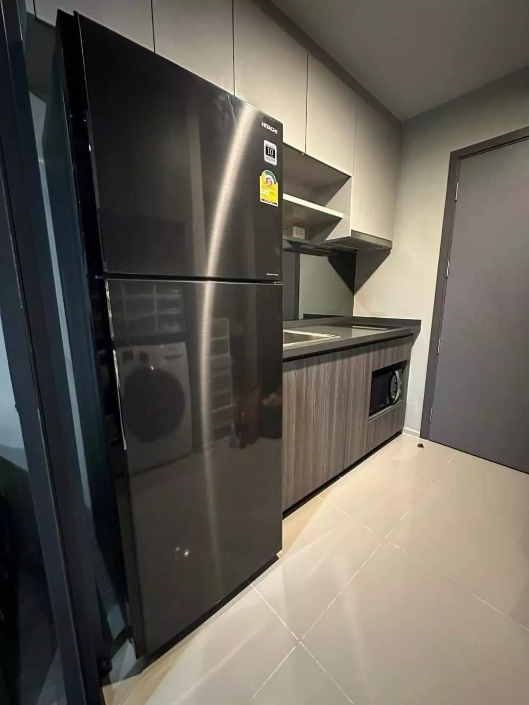 Modern kitchenette in 1-bed condo for rent at Ideo Ratchada-Sutthisan featuring grey cabinets and dark fridge