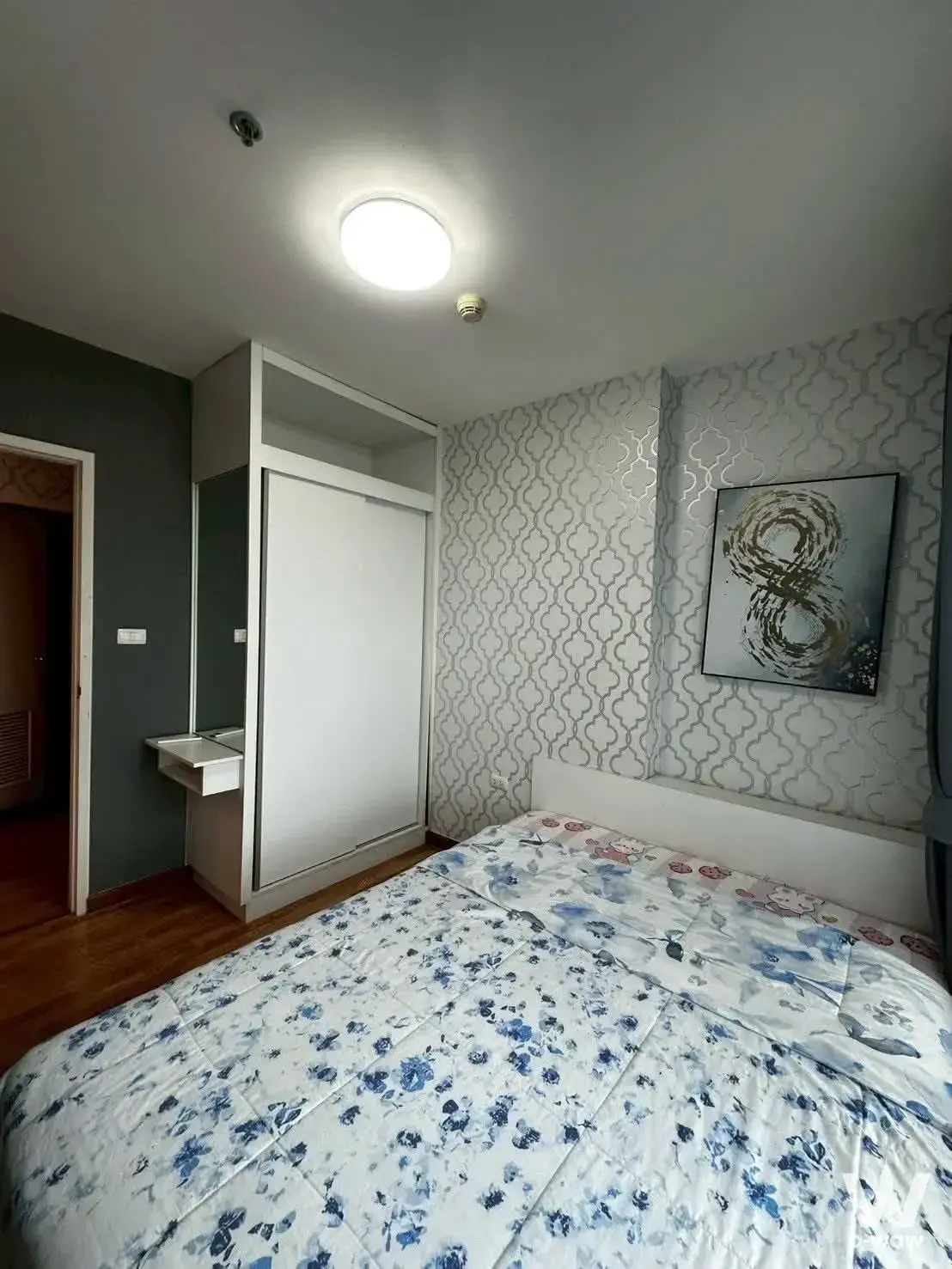 Modern bedroom in 1-bed condo for sale at The Trust Residence Pinklao with geometric wallpaper and built-in wardrobe