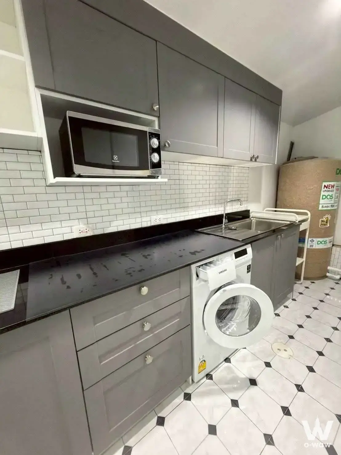 Modern kitchen with grey cabinets, black countertop, and integrated washing machine in 2-bed townhouse for rent in Siri