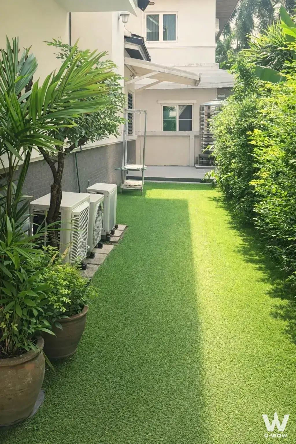 Narrow courtyard with artificial turf, AC units, and planters at 4-bed condo for sale in Baan Sansiri Pattanakarn