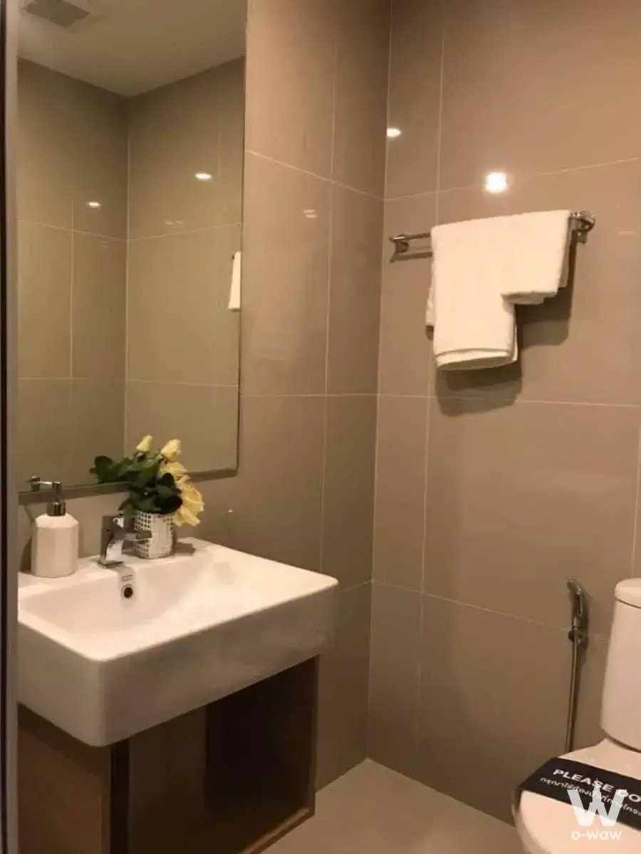 Modern bathroom with beige glossy tiles, white vessel sink, dark wood vanity, and chrome fixtures