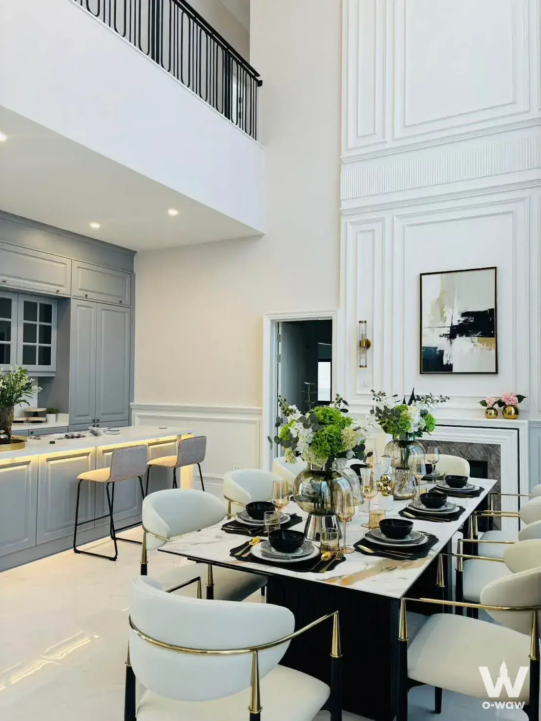Double-height dining room in a 4-bed Narinsiri Rama 9 house for sale has a white marble table and gold chairs