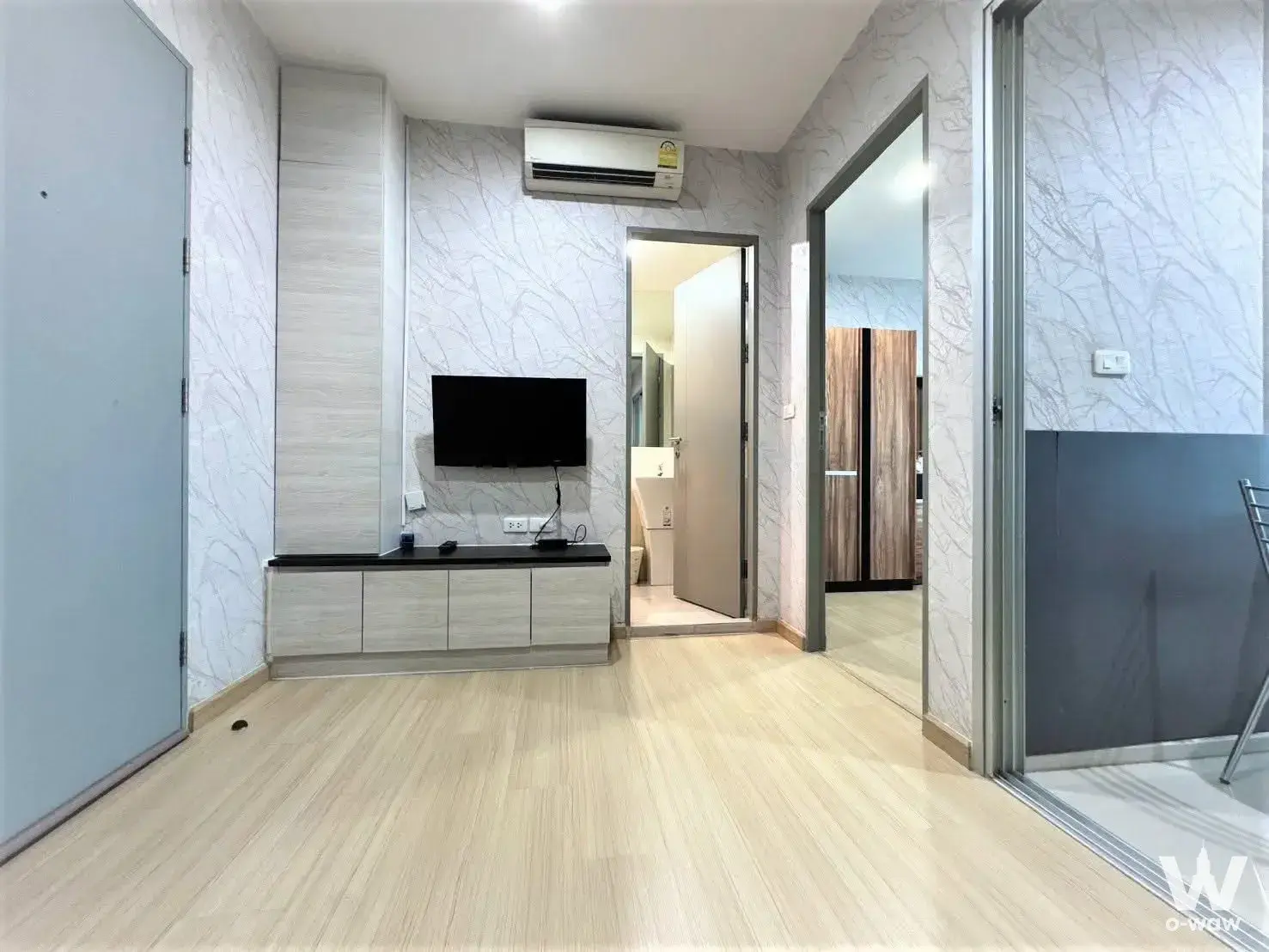 Empty 1-bed condo living room in Life Ratchadapisek with grey marble wallpaper and light wood laminate floors