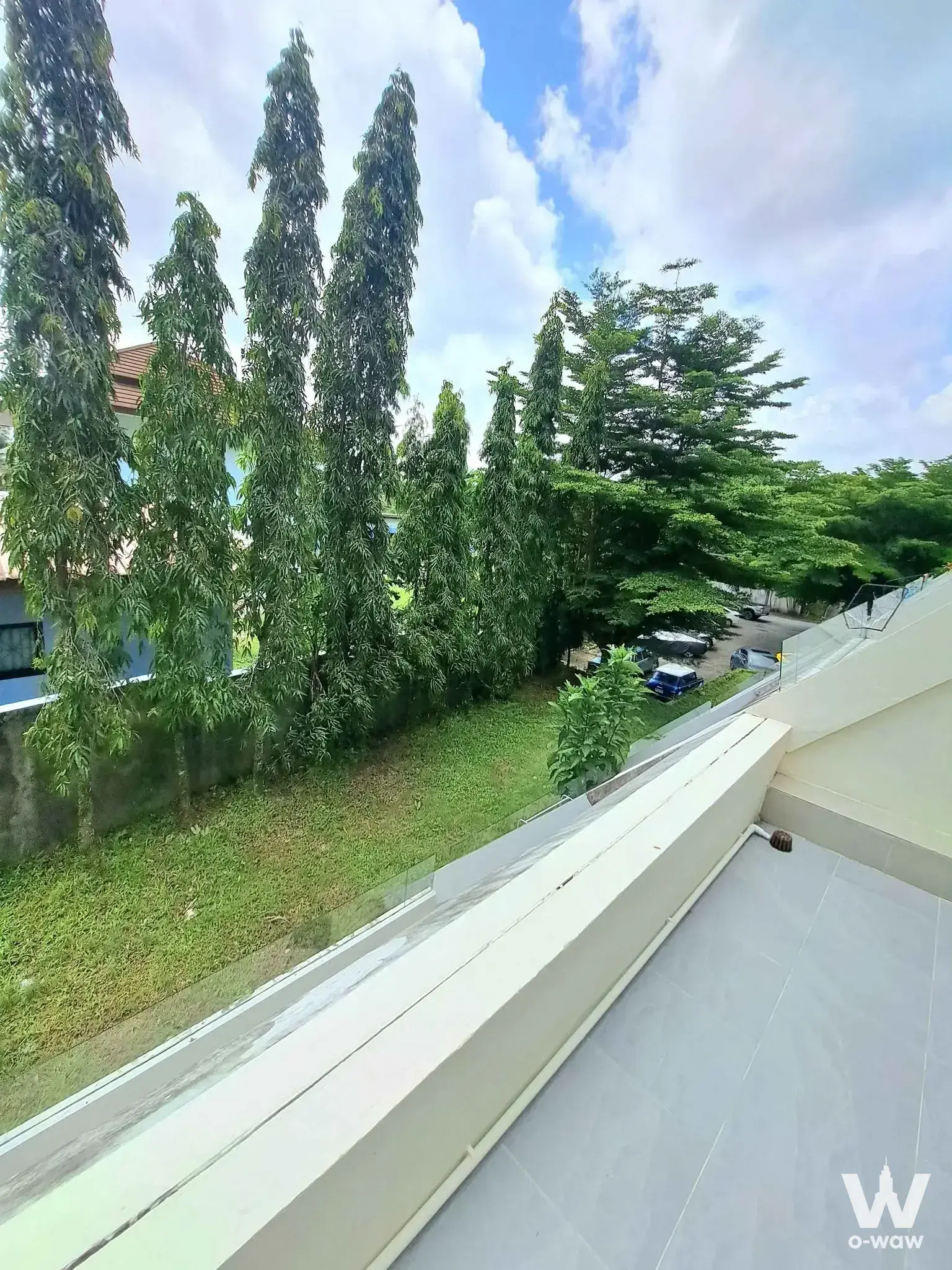 Spacious balcony with glass railing overlooking lush green trees at 1-bed condo for rent in The Green Golf Residence