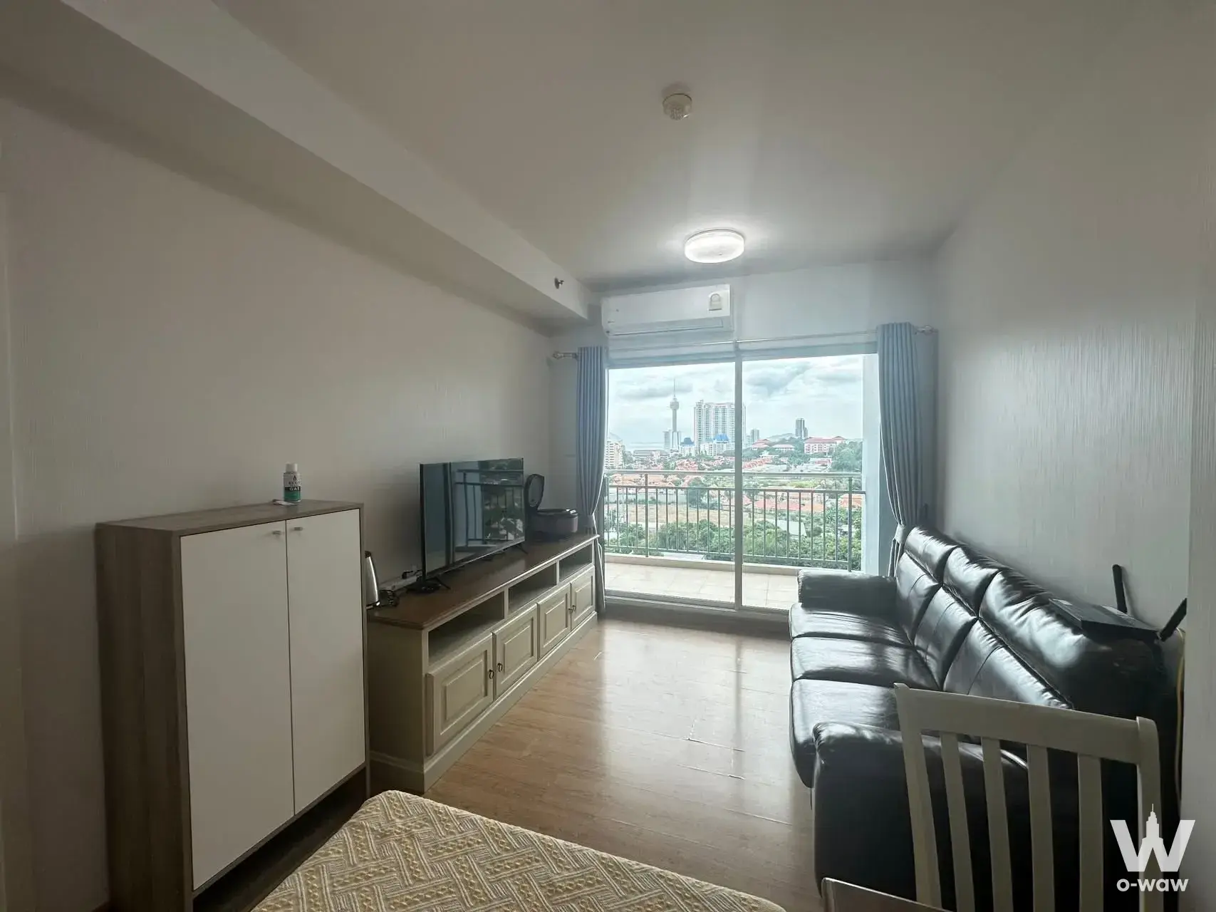 Modern condo living room with black sofa and city view from sliding doors in Supalai Mare Pattaya