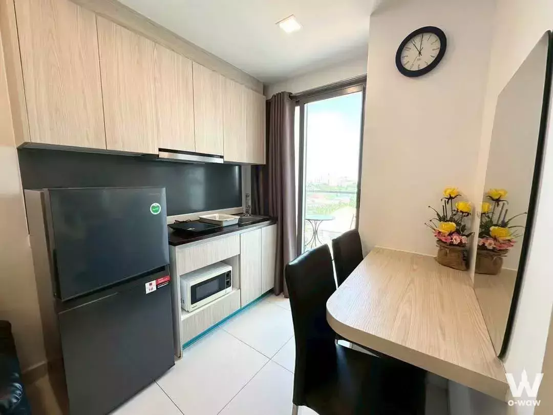 Modern 1-bed condo kitchen with light oak cabinets and black countertops in Arcadia Beach Resort Bangkok