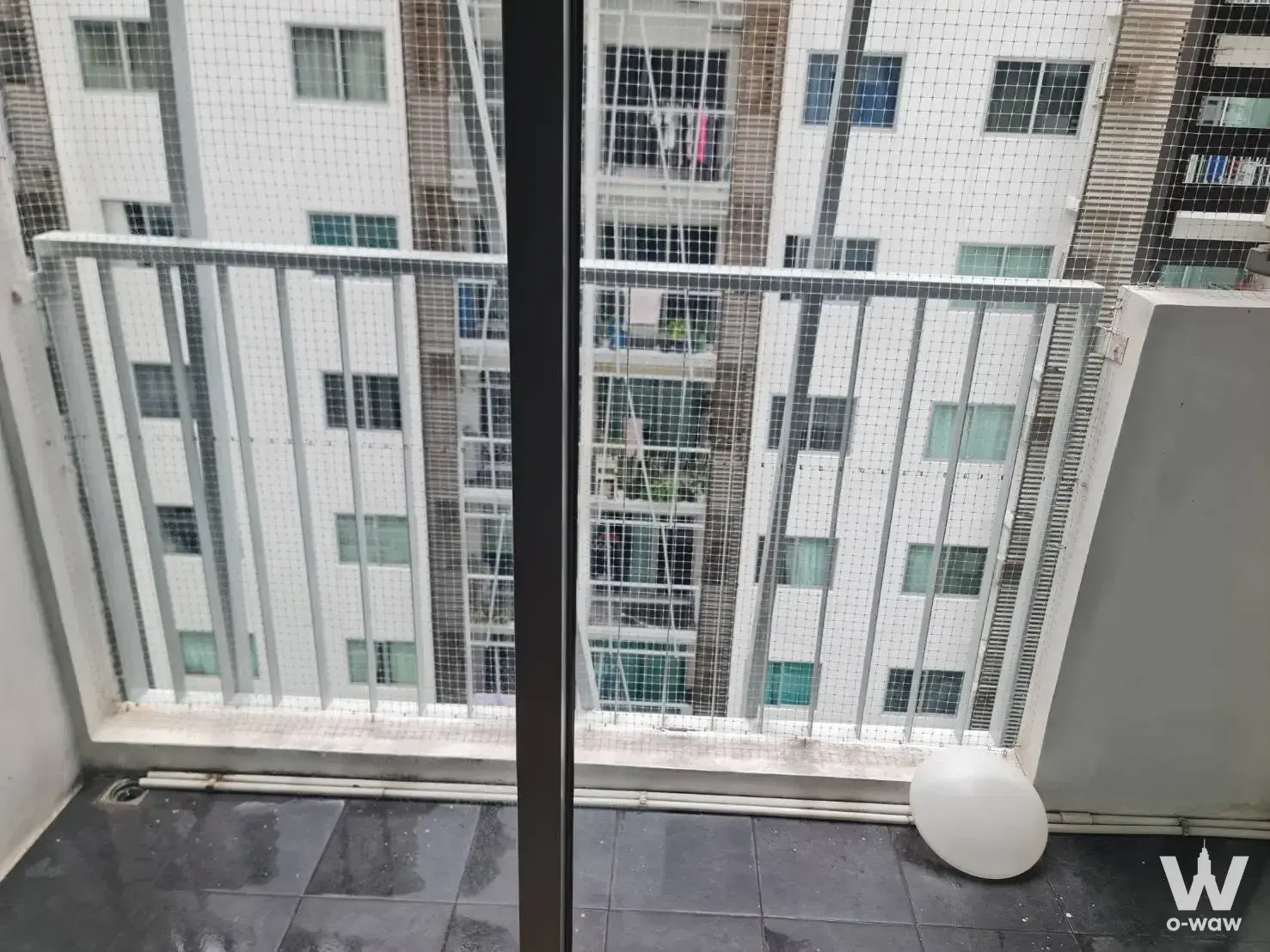 Narrow balcony with dark grey tiles and mesh security screen at Aspire Asoke-Ratchada