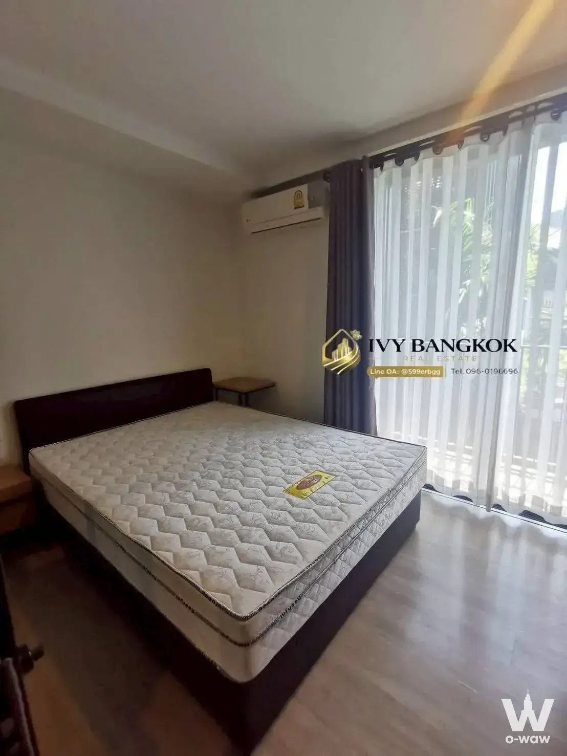 Spacious bedroom in 1-bed Maestro 02 Ruamrudee condo with garden view and wooden furniture