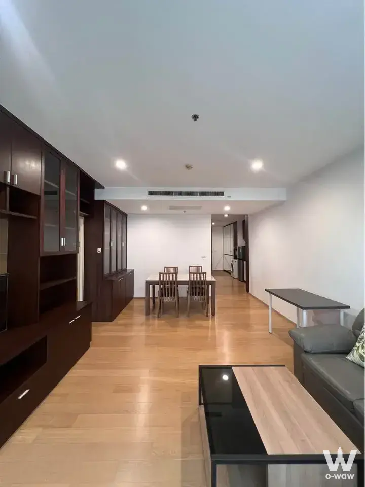Modern living and dining area with espresso cabinetry, grey sofa, and wood table in 1-bed rental at Noble Reflex Bangkok