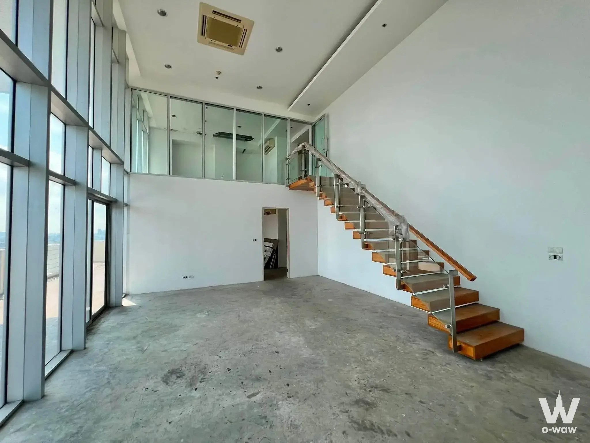 The open-plan loft in a 2-bed condo in My Resort Bangkok has high ceilings, concrete floors and floor-to-ceiling views