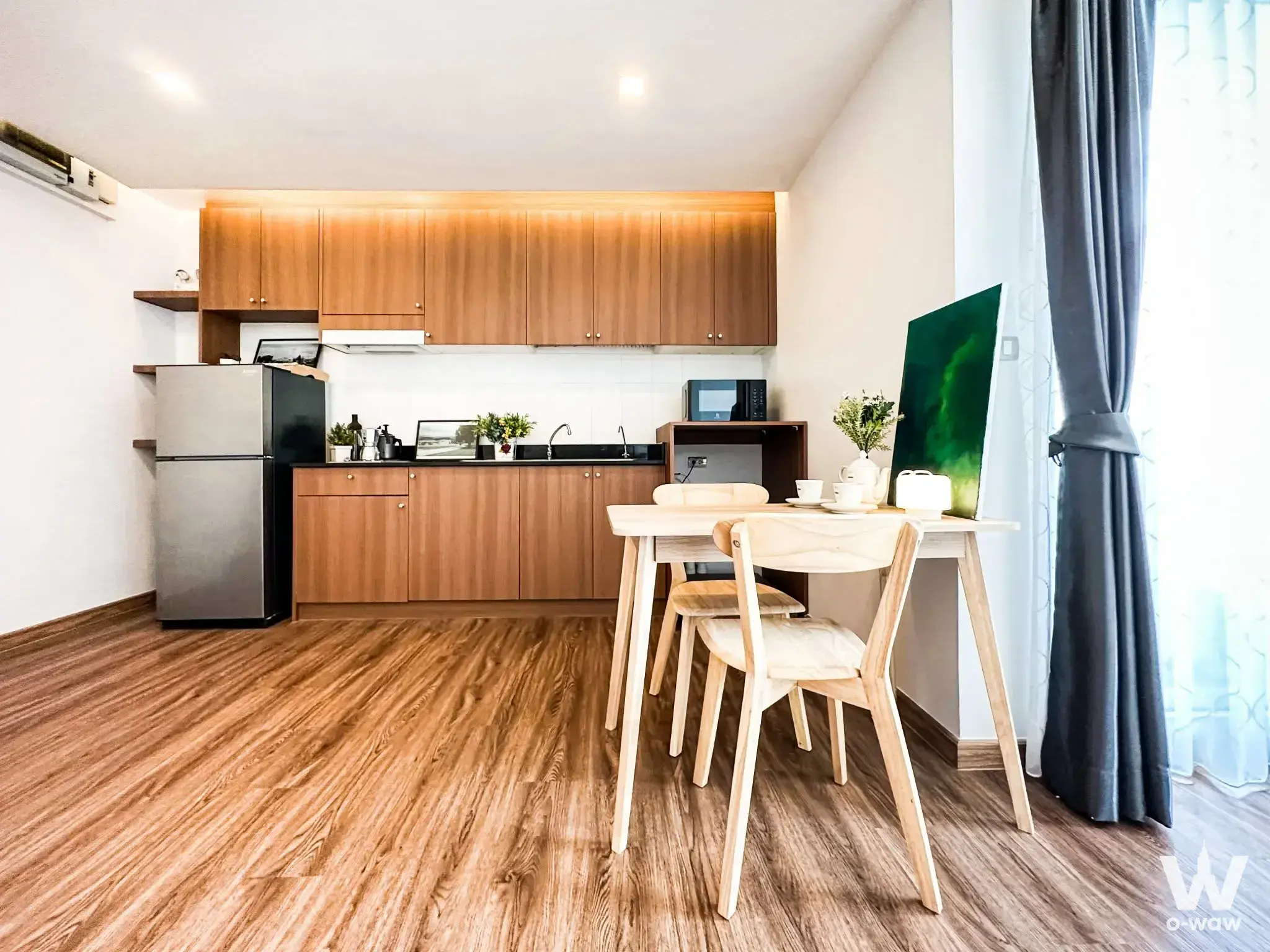 Modern 1-bed condo kitchen at Tree Condo Sukhumvit 42 with wooden cabinets, dining table, and floor-to-ceiling windows