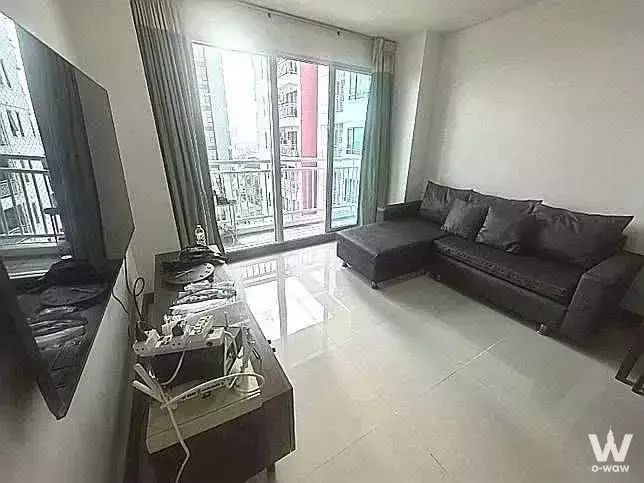 Modern living room in 2-bed condo for sale at The Kith Plus Sukhumvit 113 with grey sofa and balcony views