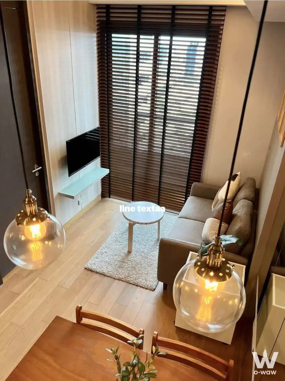 Modern living area in 1-bed condo for rent at The Lumpini 24 with grey sofa, mint shelf, and pendant lights