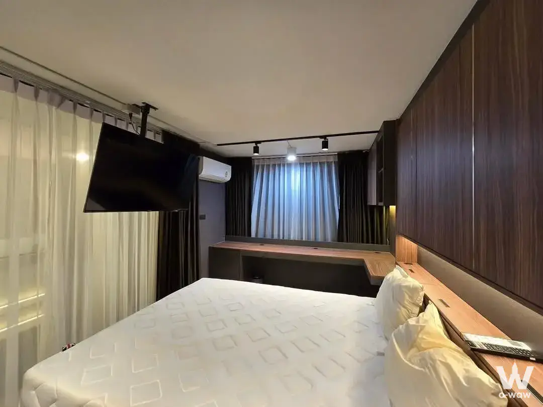 Fully furnished bedroom in Ideo Charan 70 Riverview featuring dark wood wardrobe and window desk
