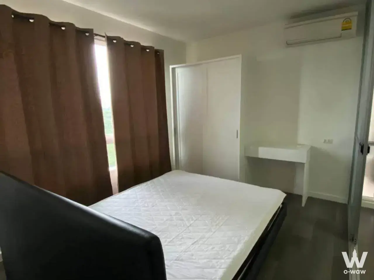 Queen bed with black headboard in a bright bedroom of this dcondo Campus Resort Rangsit rental