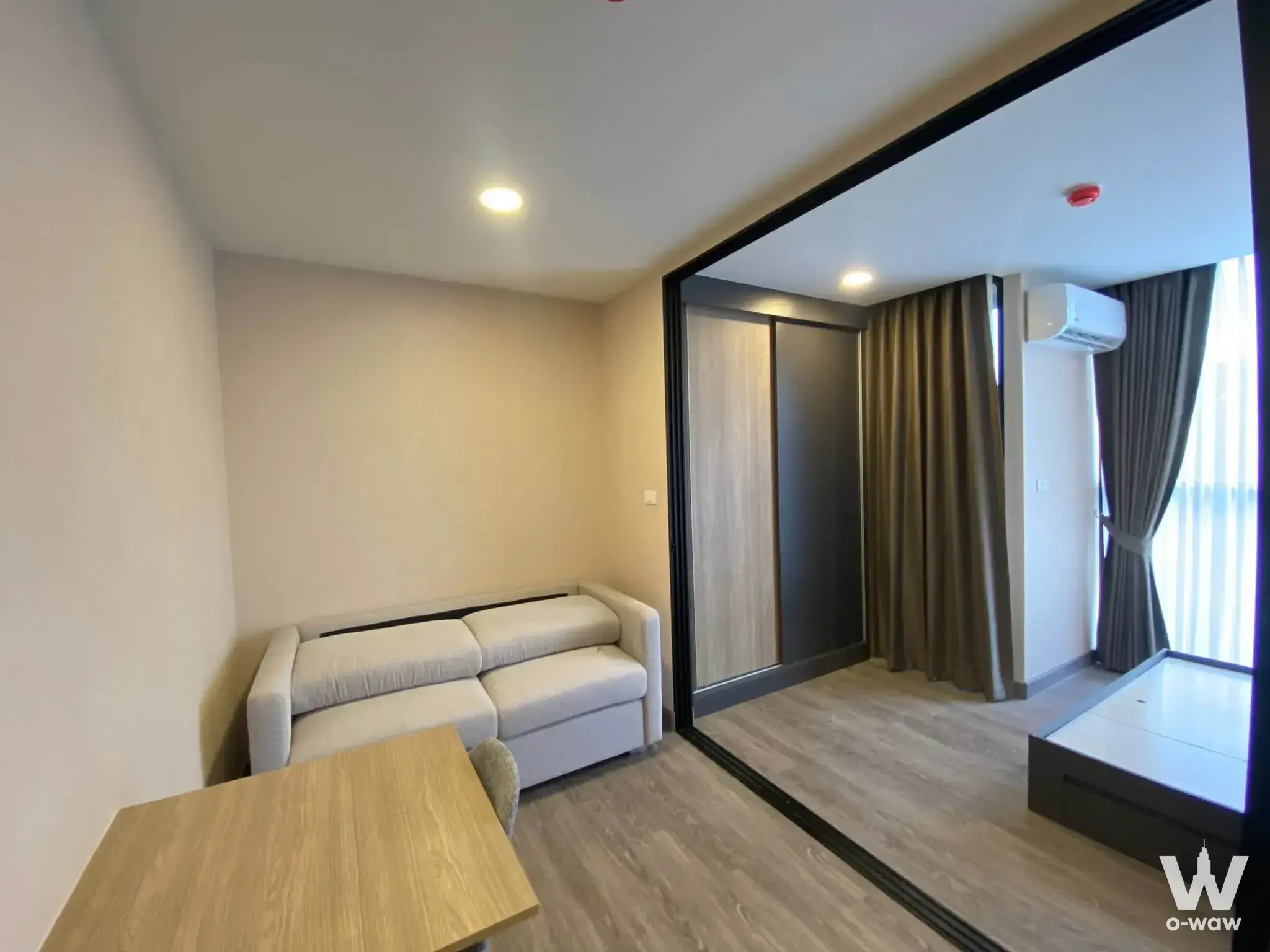 Modern 1-bed condo for sale in FLEXI Sathon-Charoen Nakhon with open-plan layout, grey laminate floors, and glass sliding