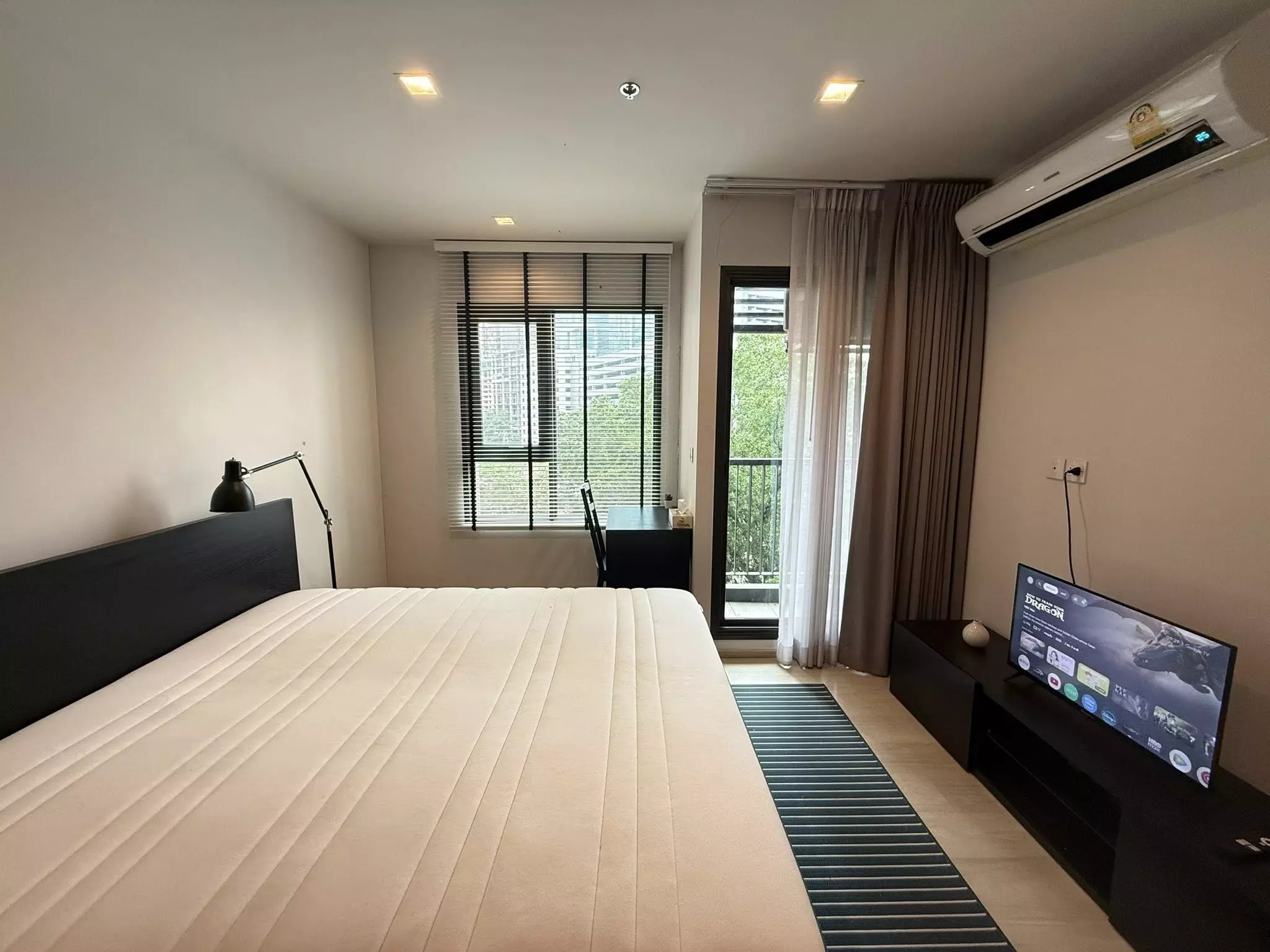Modern bedroom in 1-bed Life One Wireless condo with espresso bed, TV console, and balcony access
