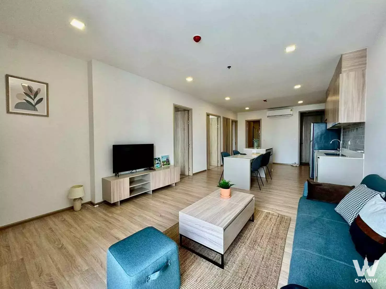 Modern open-plan living area in 2-bed condo for rent at XT Phayathai featuring teal sofa, marble coffee table, and sleek