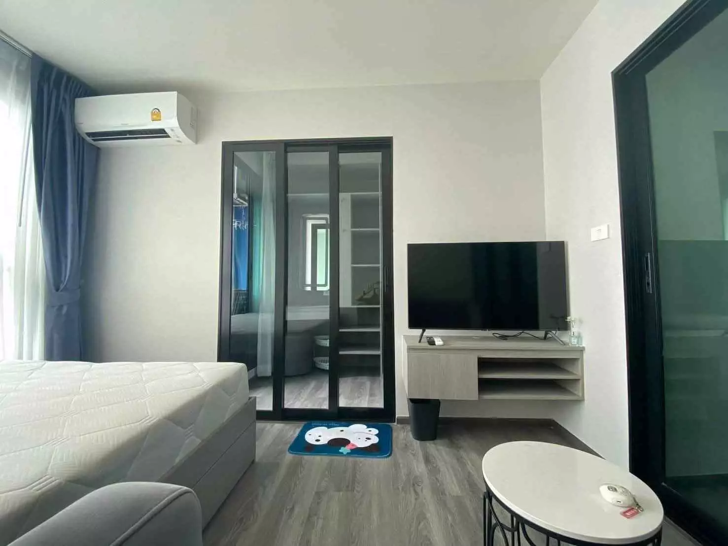 Bright 1-bed condo bedroom at The Origin Onnut with grey flooring, queen bed, and sliding glass doors