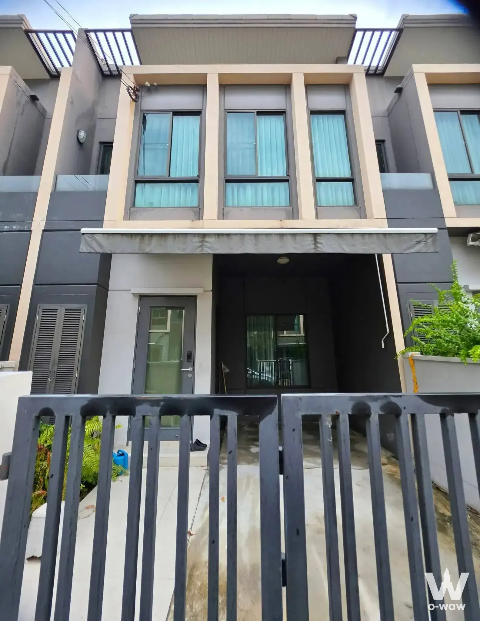 Three-story townhouse exterior with dark facade and pergola in Pleno Sukhumvit-Bangna 2