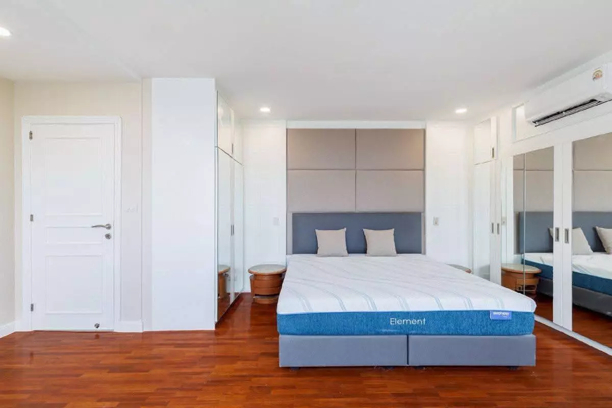 Modern bedroom in 3-bed condo for sale at President Park with wood floors, grey bed, and mirrored wardrobes