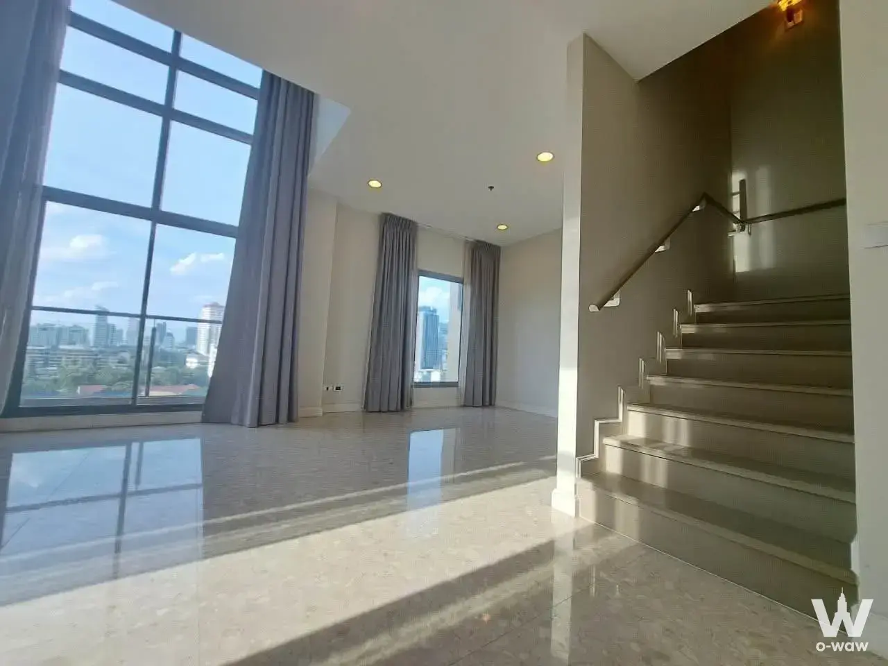 Duplex living area in The Crest Sukhumvit 34 condo with marble floors, bronze staircase, and city views