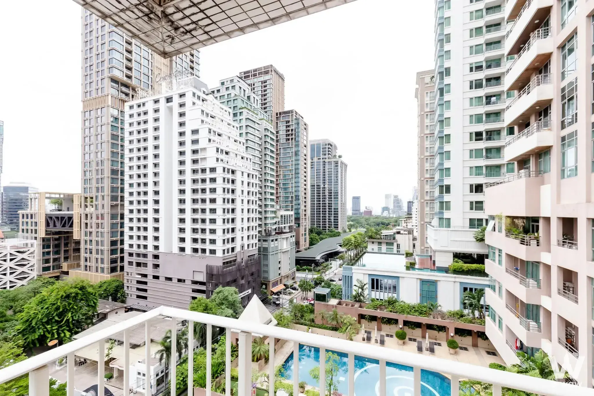 Balcony with white railing overlooking blue pool and Bangkok skyline at LangSuan Ville 3-bed condo for sale