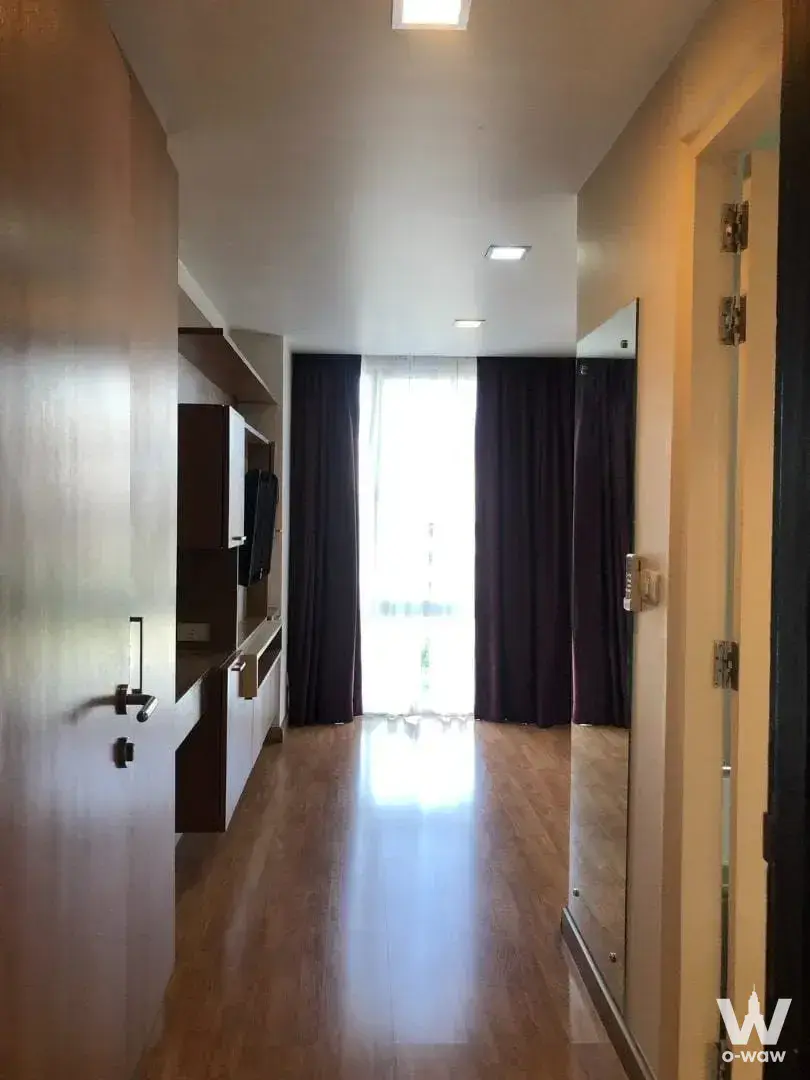 Modern entryway with glossy wood floors and built-in shelving in 2-bed condo for sale at The Alcove 49 Bangkok
