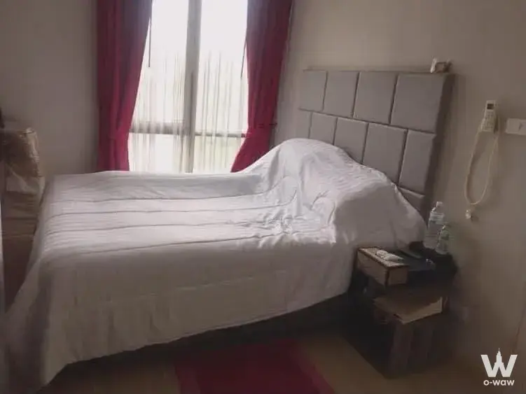 Queen bed with grey headboard and red drapes in this 1-bed condo for rent at The Unique Lat Phrao 26