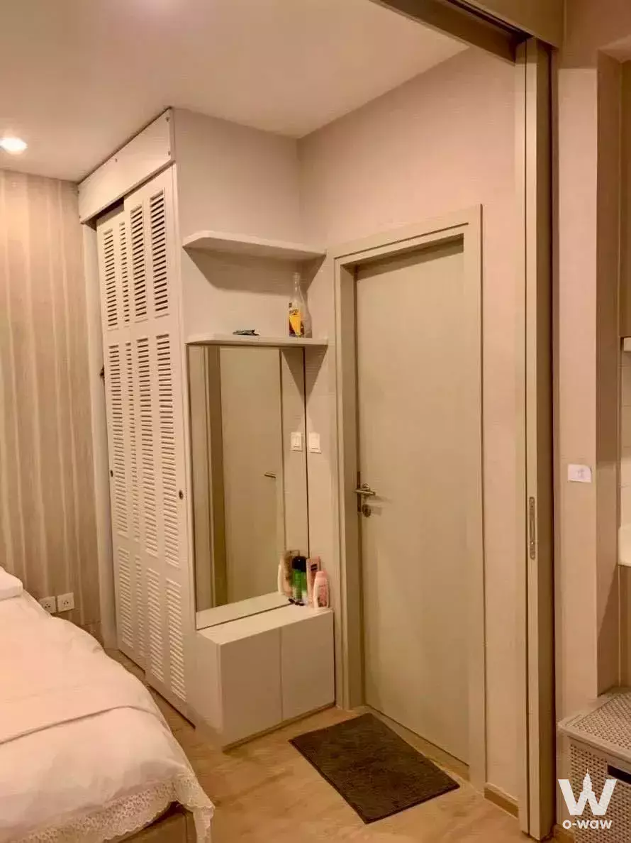 Modern bedroom in 1-bed Ideo Q Chula-Samyan condo with white built-in storage and light wood floors