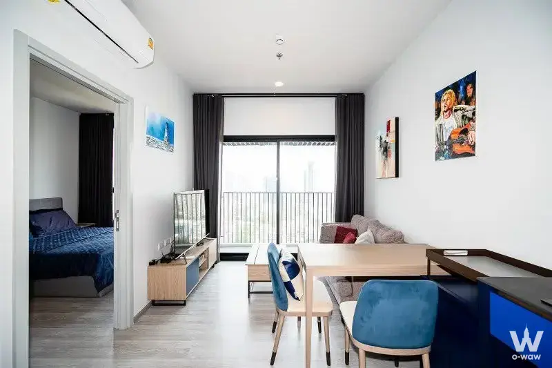 Modern 1-bed condo for rent in XT Ekkamai with grey sofa, teal chairs, and balcony city views