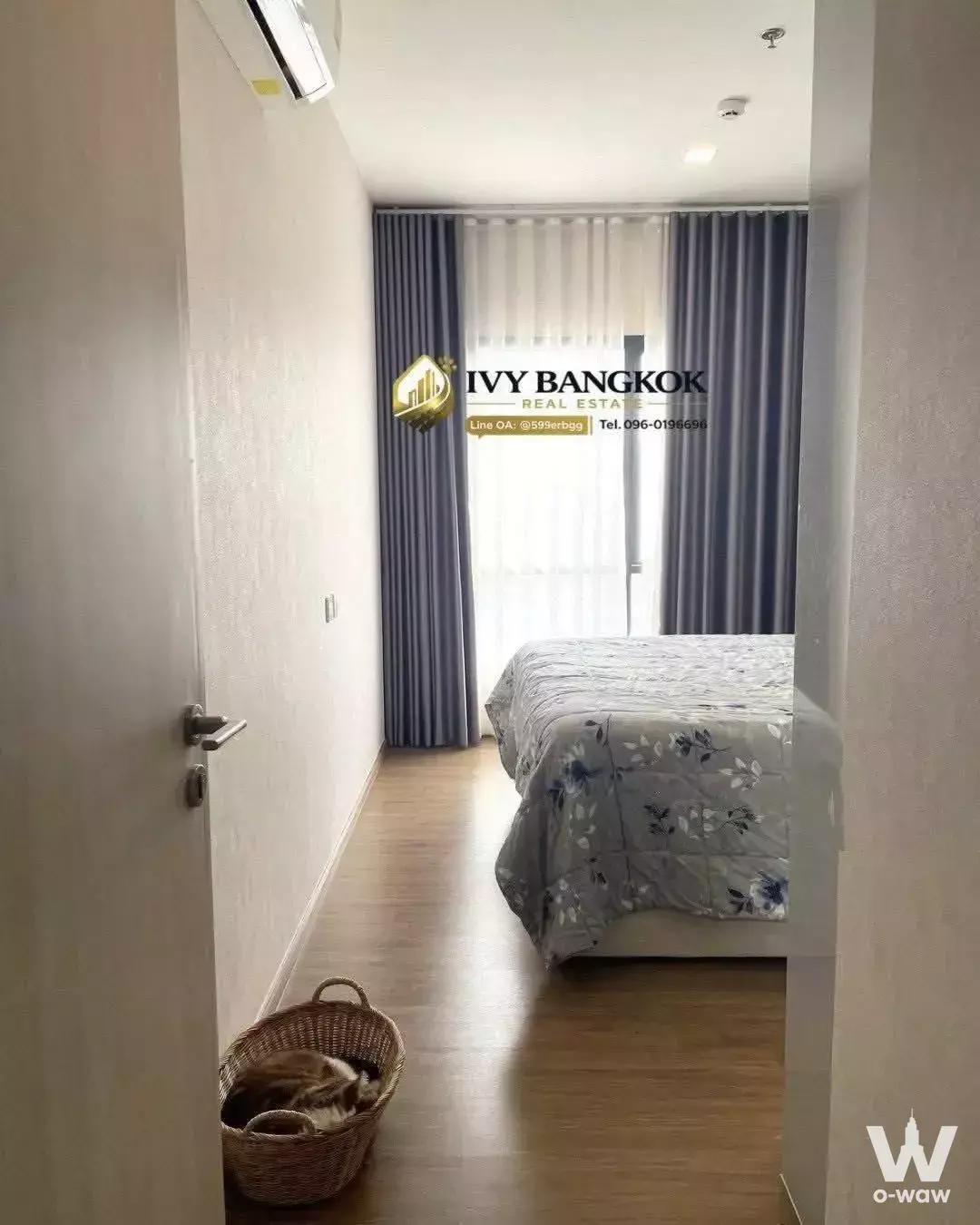 Modern bedroom with grey floral bedding, sheer curtains, and a sleeping cat in a 2-bed condo for rent at Metris Rama