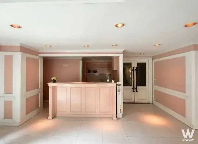Pastel pink reception lobby with wooden desk in a 2-bed condo for sale at La Vie en Rose