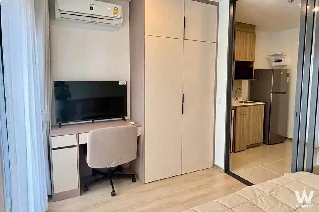 Condo bedroom corner with a built-in desk, TV, and sliding door to the kitchenette in this Life Rama 4 rental