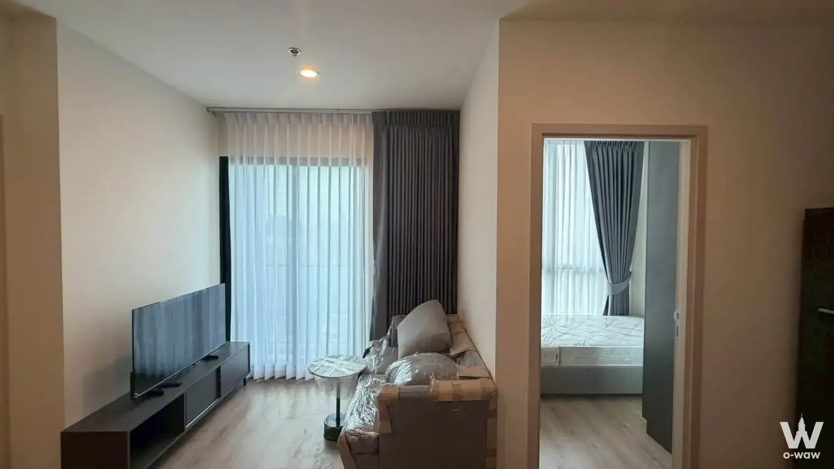 Modern 2-bed condo living room and bedroom in Nuea District R9 with floor-to-ceiling windows and pale wood floors