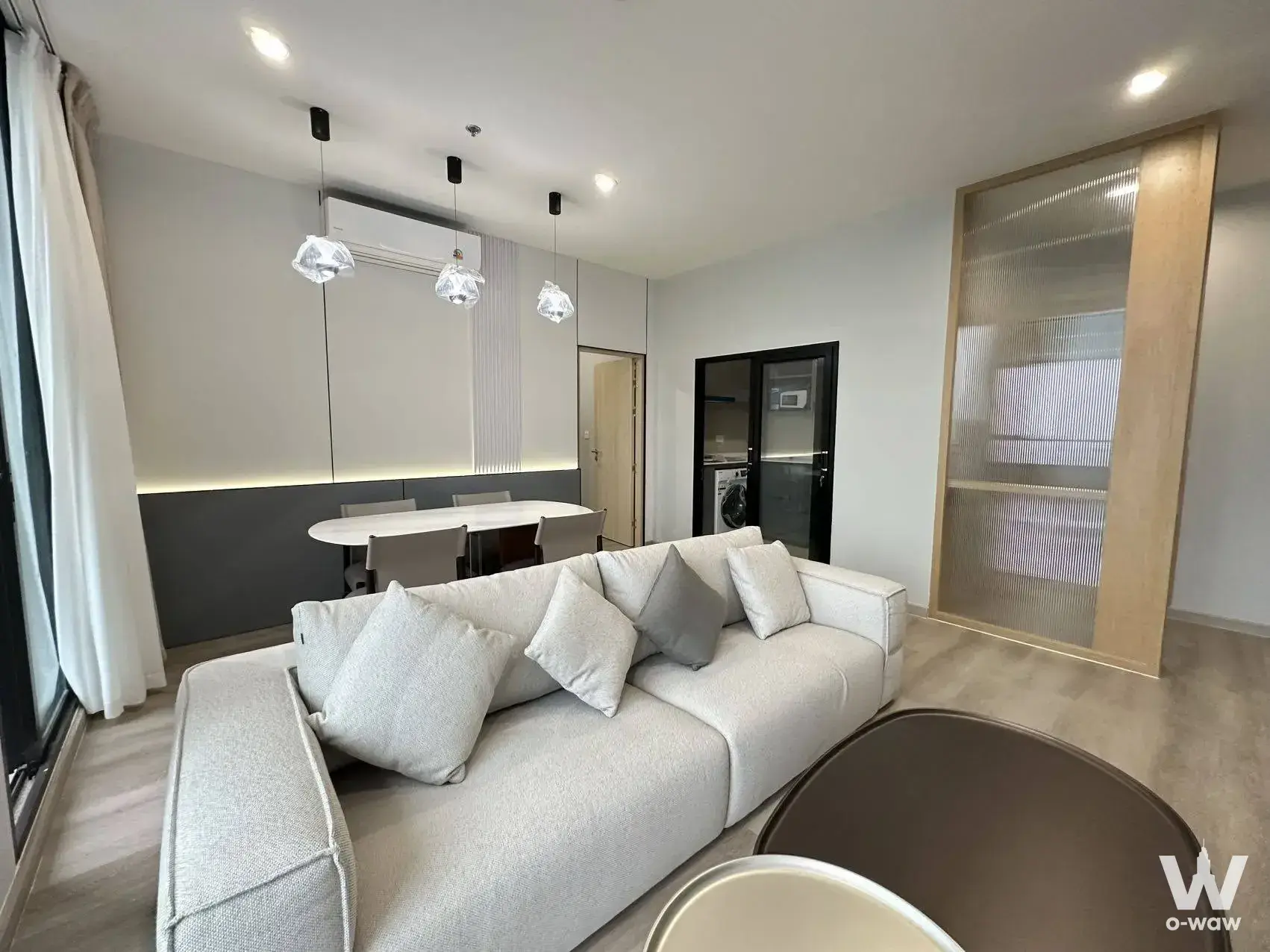 Living area in a 3-bed Sukhumvit 64 condo with L-shaped sofa and pendant lights over the dining table