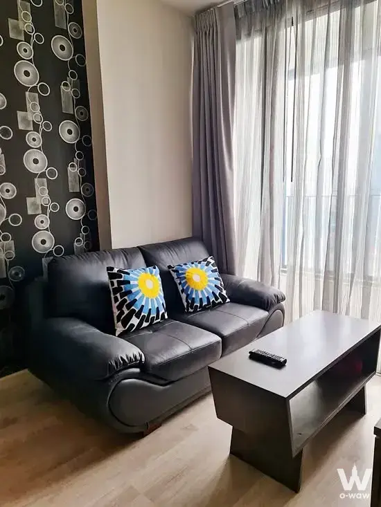 Living room in Ideo Mobi Sathorn with black leather sofa and geometric feature wall
