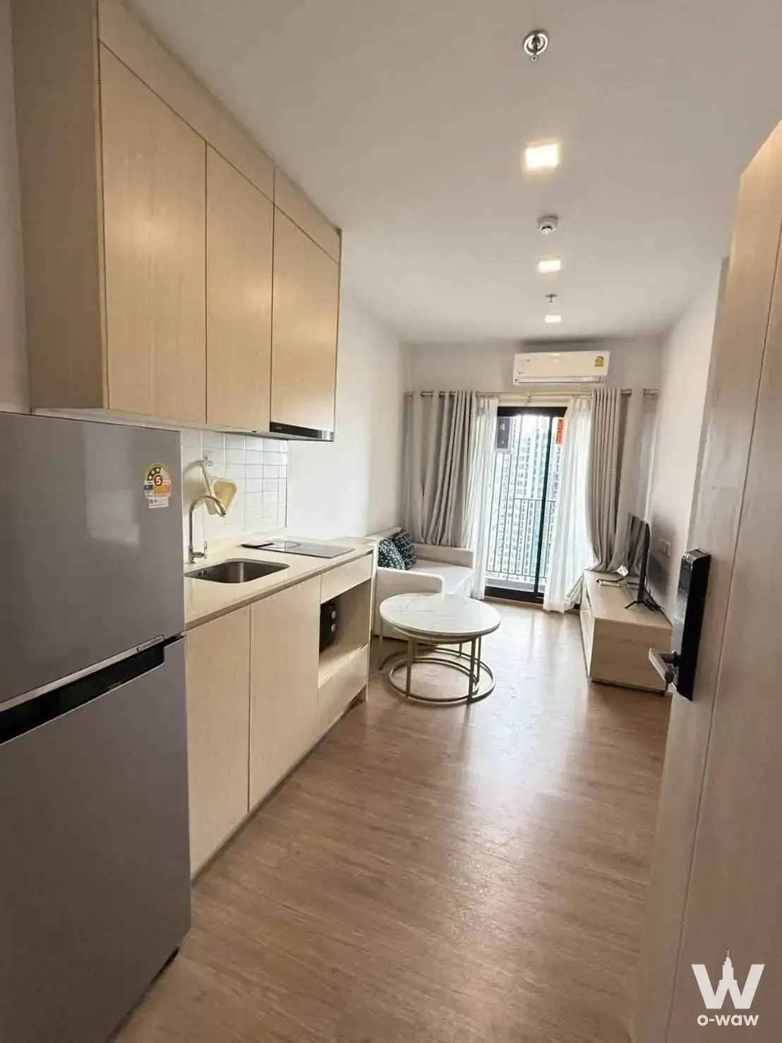 Furnished 1-bed condo for sale in Metris Rama 9-Ramkumhang featuring an open-plan living area with light wood floors and