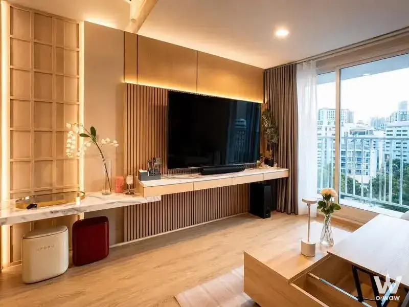 Modern living room with oak floors, LED entertainment wall, and balcony access in Culture Chula 2-bed rental