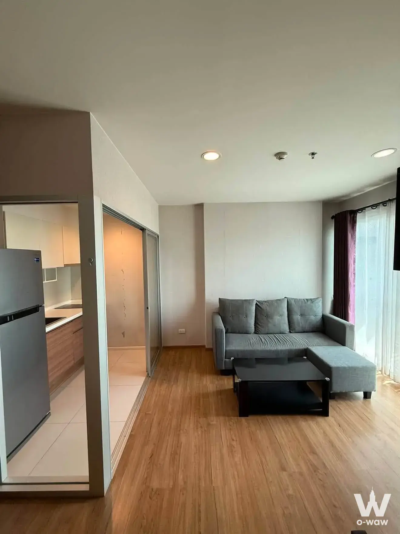 Open-plan living room in a 1-bed Fuse Chan Sathorn rental with grey sectional sofa and wood flooring