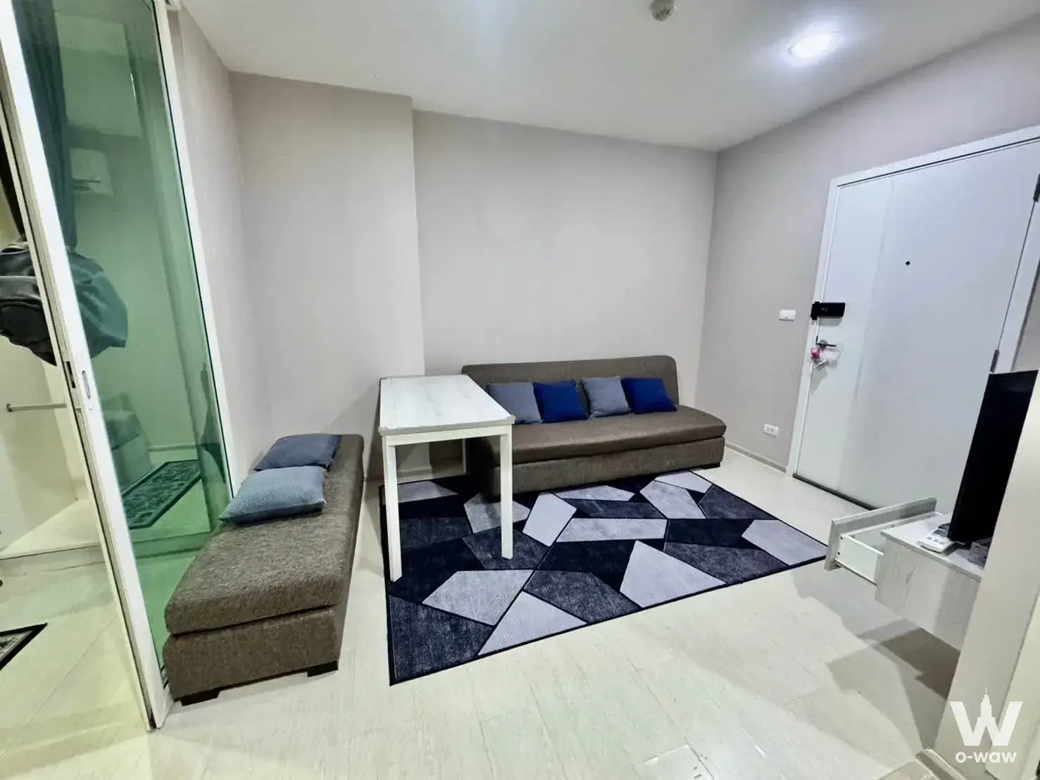 Aspire Erawan Prime 2-bed condo living room with brown sofa and geometric navy rug