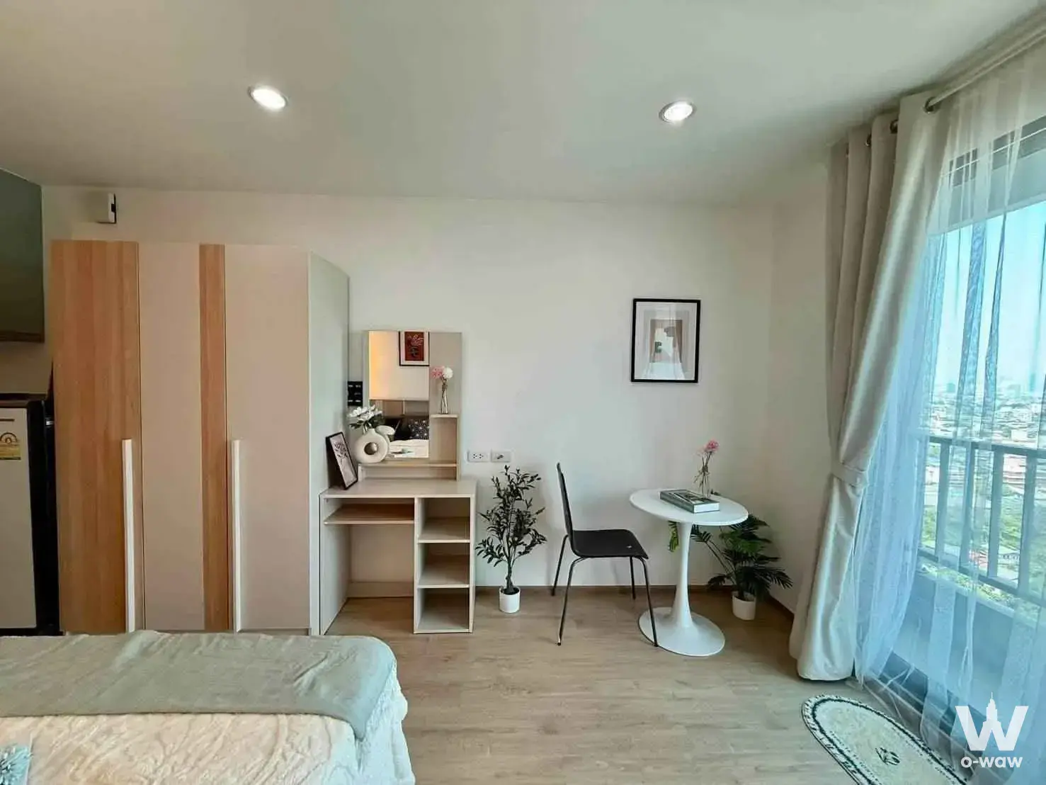 Bright 1-bed condo bedroom in Ideo Wutthakat with light wood floors, sage green accents, and city views