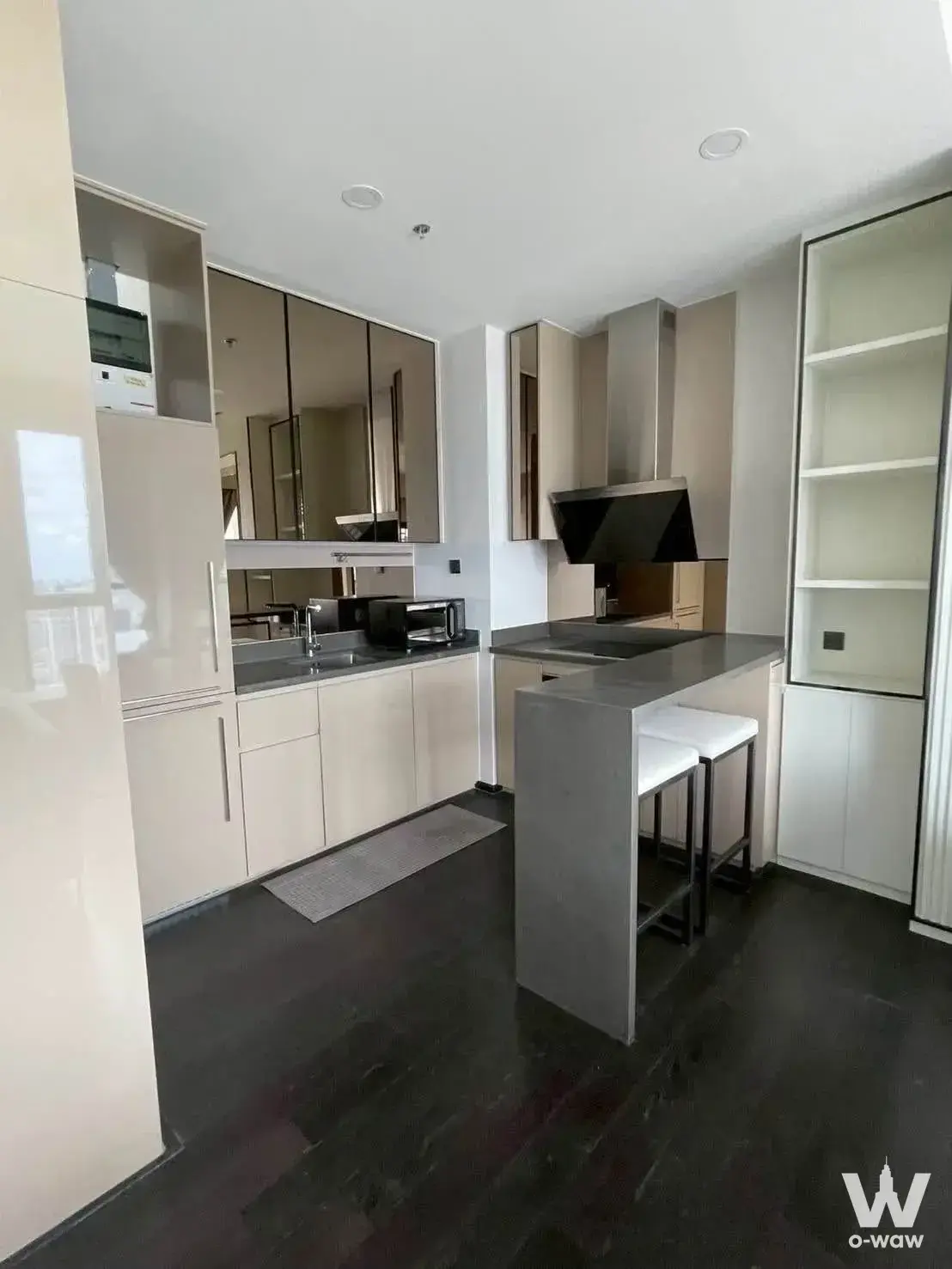 Park Origin Thonglor 2-bed condo kitchen with bronze mirror cabinets, grey island, and bar stools