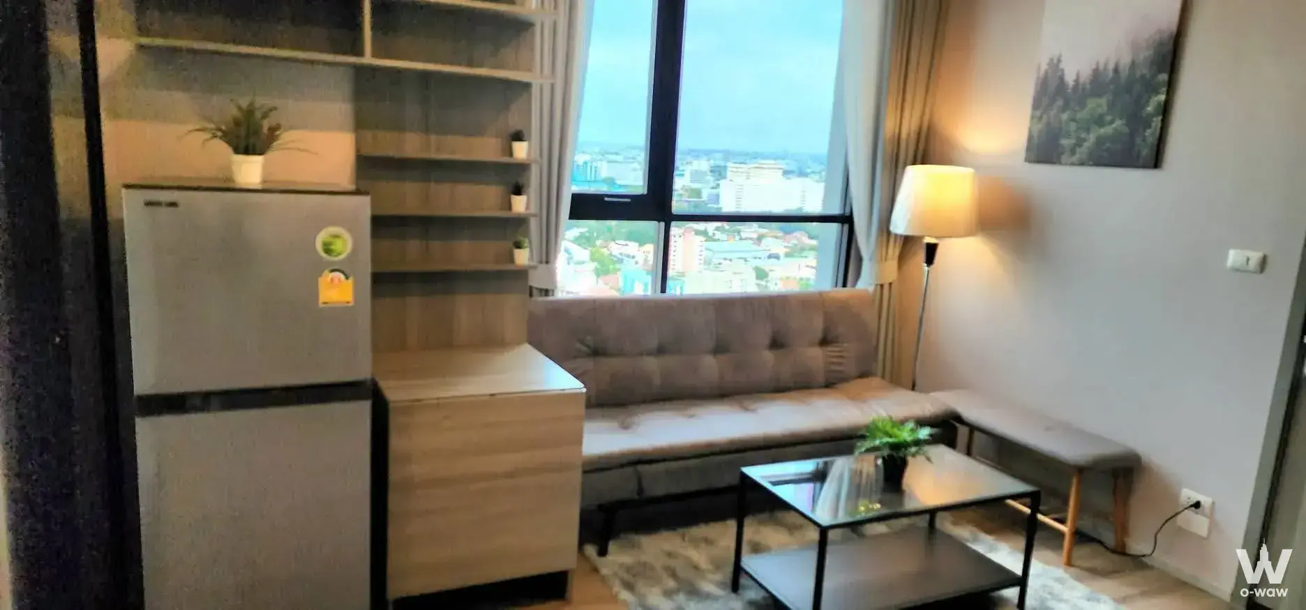 Compact living room in KnightsBridge Prime Ratchayothin with tufted sofa and high-floor city skyline view