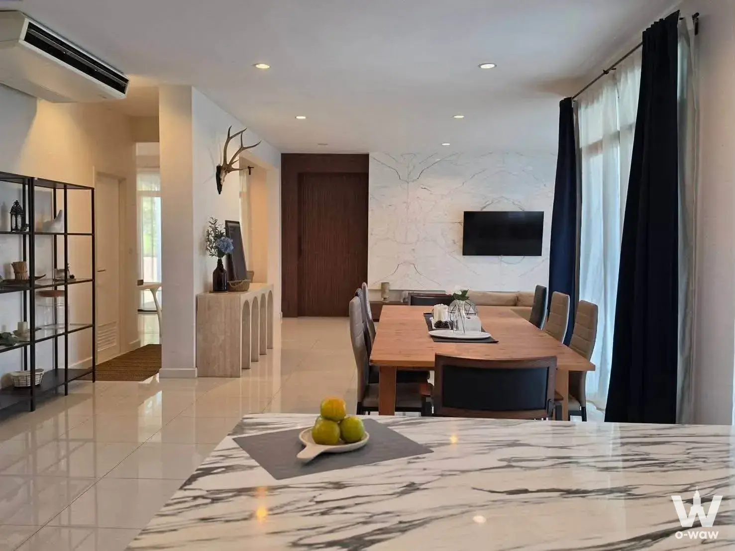 This open-plan dining area in a 4-bed The Palm Pattanakarn rental house has a marble island and wall-mounted TV